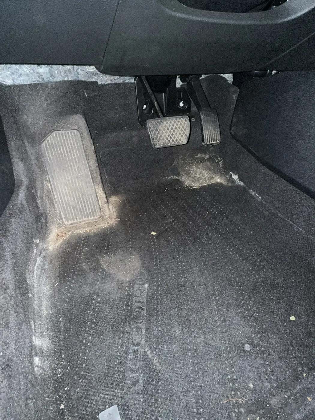 Acura driver footwell, salt stains and dirt around the pedals and heel pad