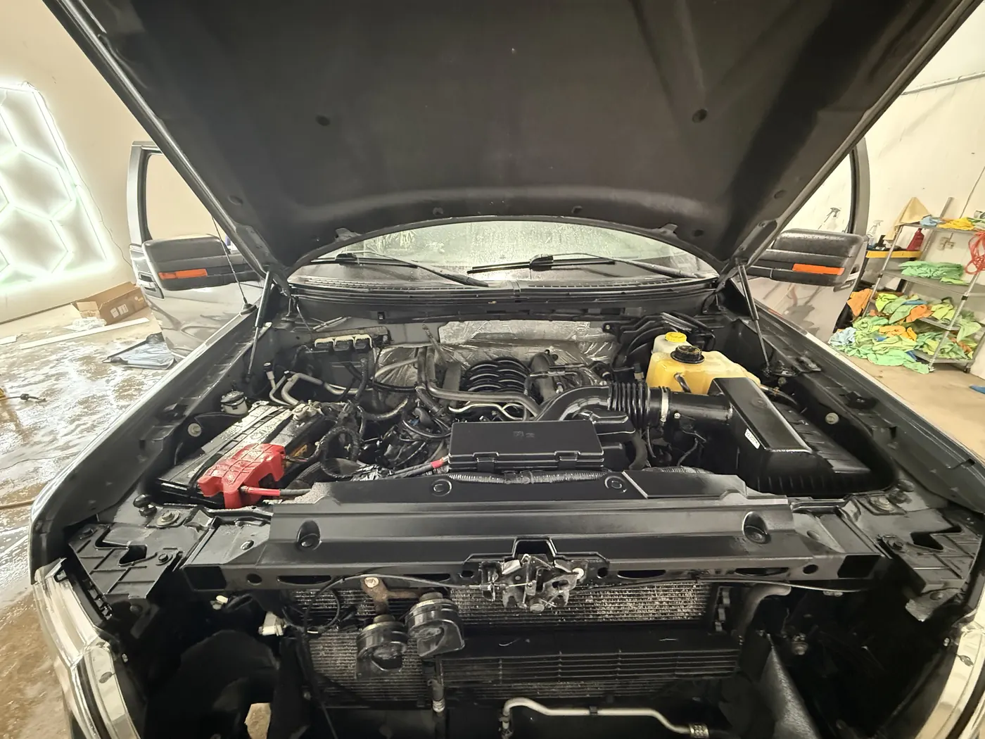 The same pickup engine bay after cleaning, plastics dark and the hood liner clean