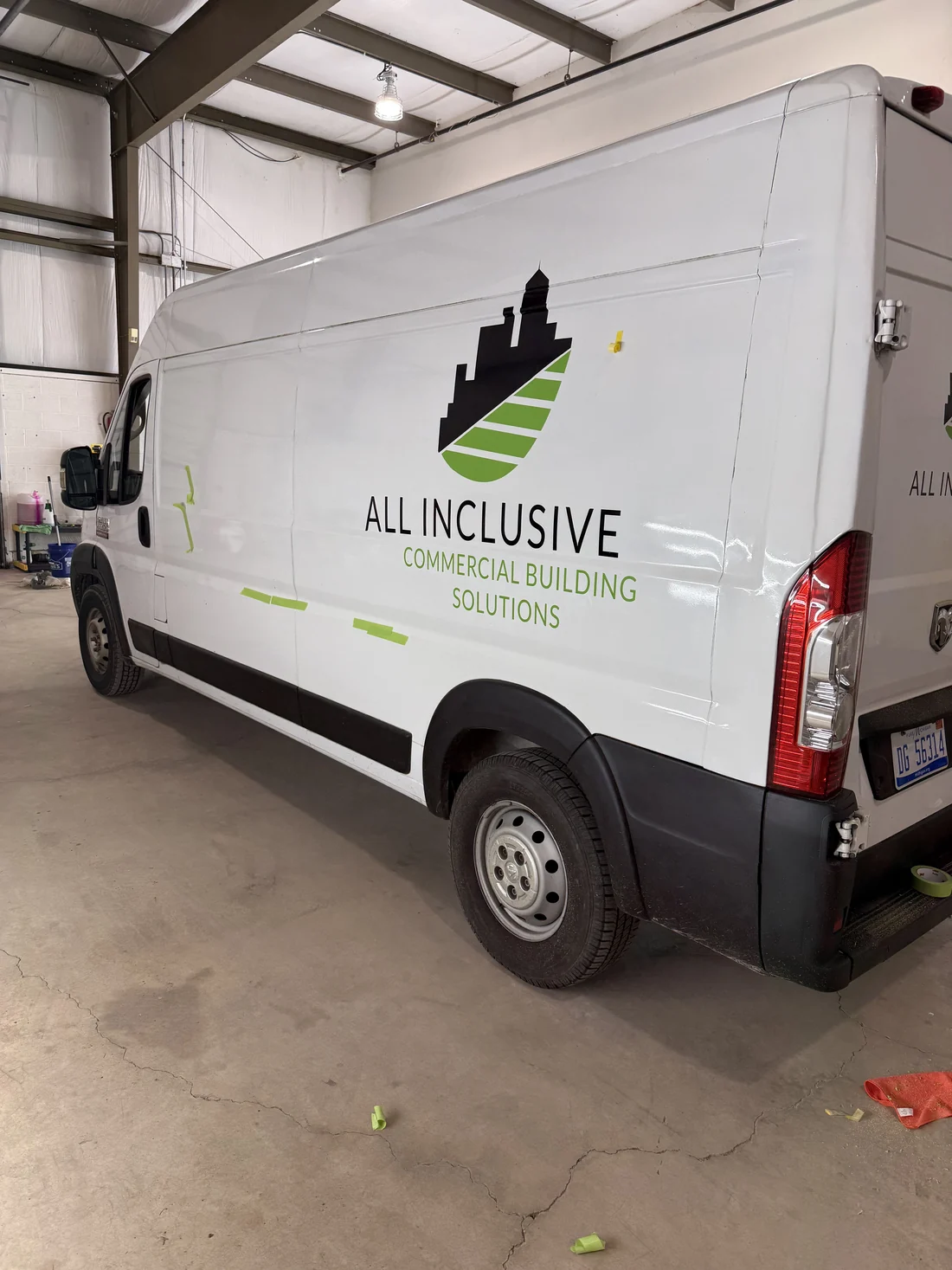 White Ram ProMaster van in the A2 Auto Works bay with All Inclusive Commercial Building Solutions graphics on the side, vinyl offcuts on the floor